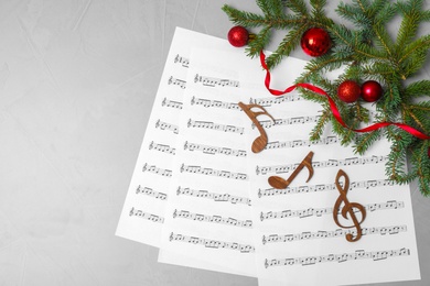 Photo of Flat lay composition with Christmas decor, music sheets, wooden notes and space for text on grey background