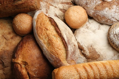 Photo of Different kinds of delicious bread as background, top view