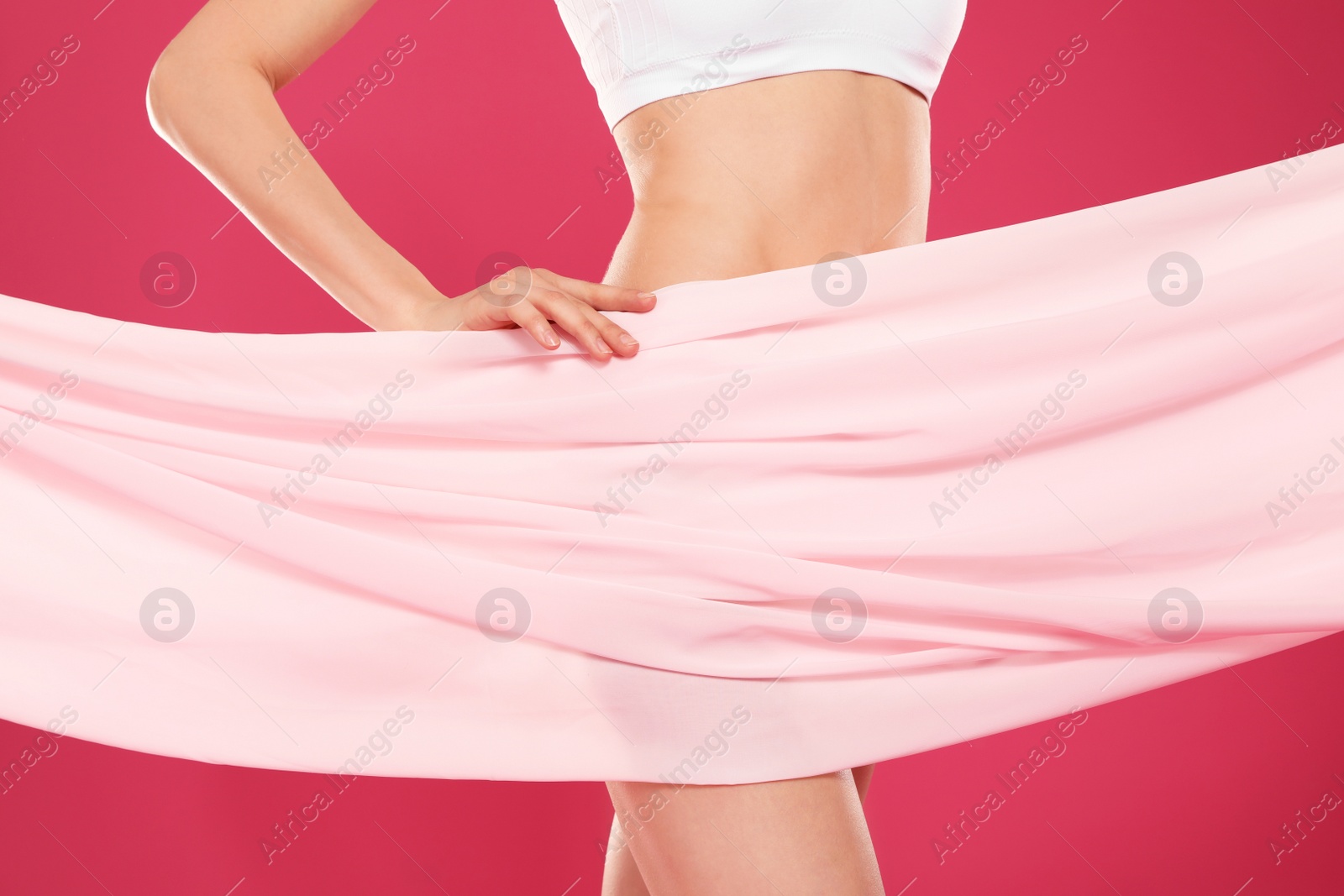 Photo of Slim young woman covered with silk fabric on color background, closeup. Fit body