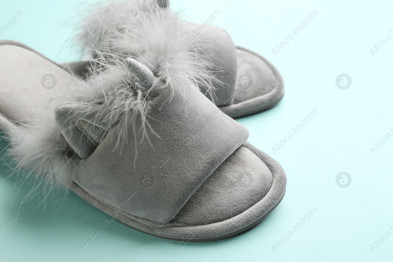 Photo of Pair of stylish soft slippers on turquoise background, closeup