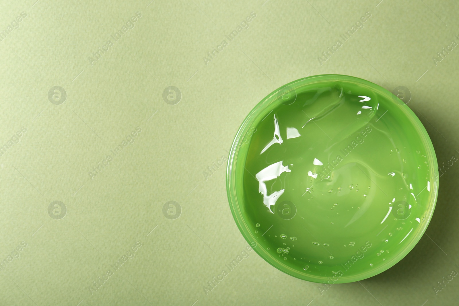 Photo of Aloe gel in jar on olive background, top view. Space for text