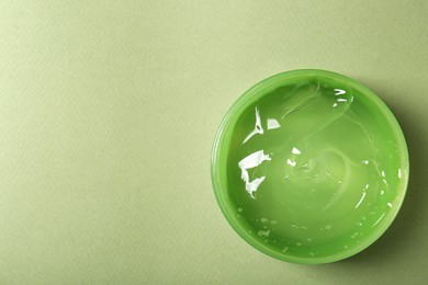 Photo of Aloe gel in jar on olive background, top view. Space for text