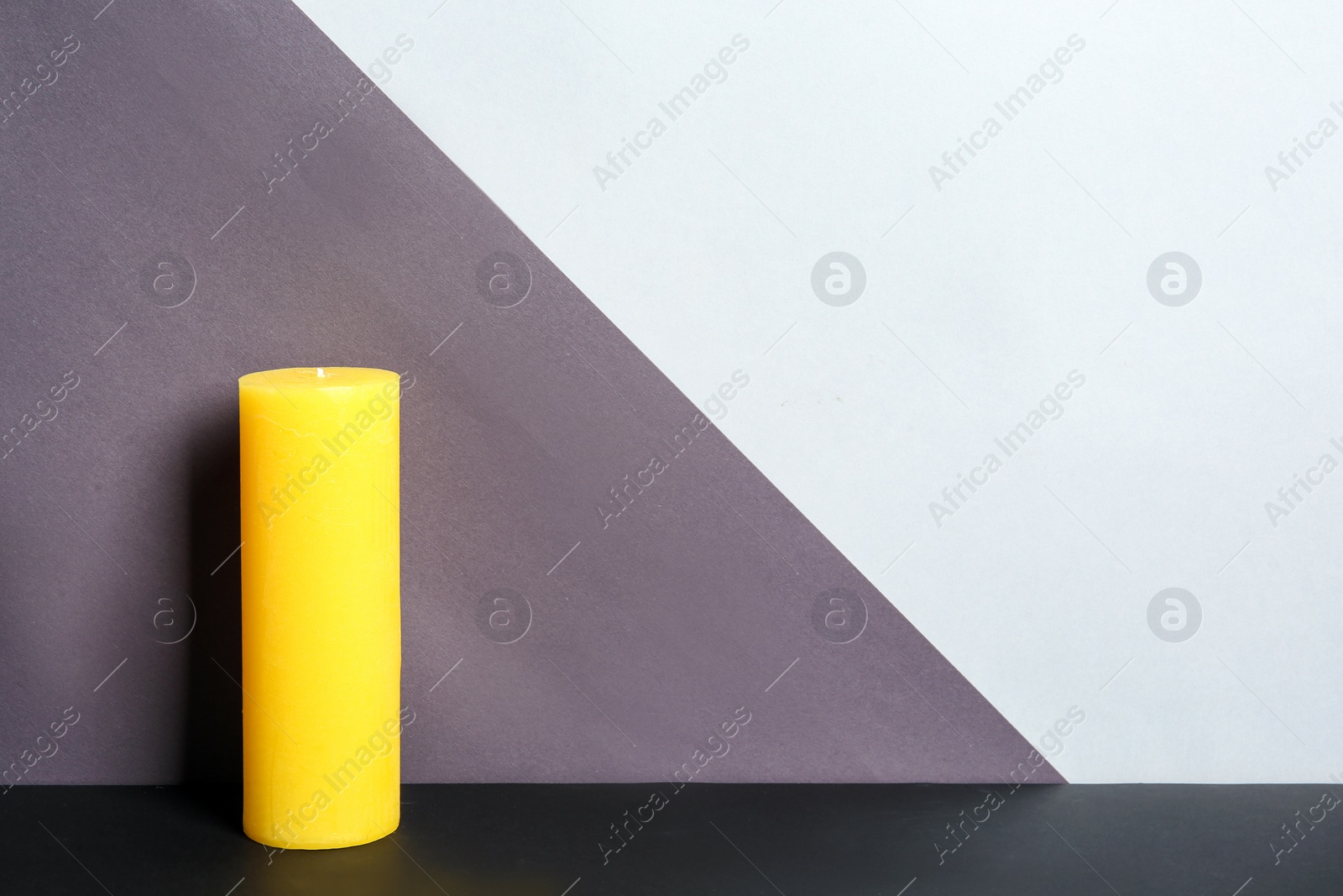 Photo of Decorative wax candle on table against color background