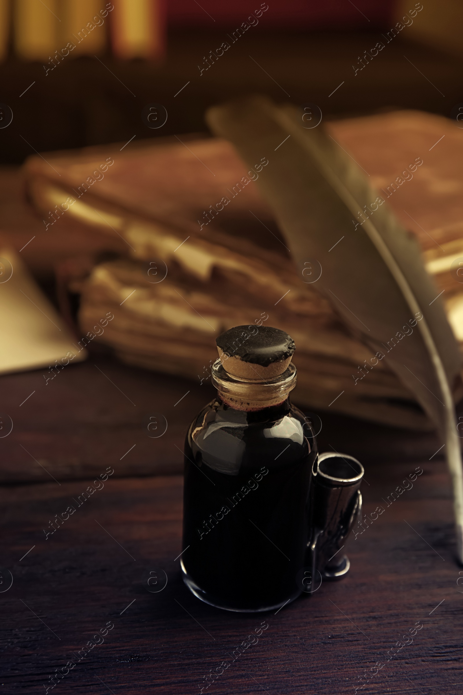 Photo of Feather pen and bottle of ink on wooden table