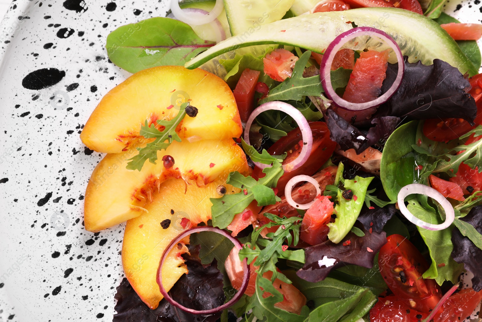 Photo of Delicious salad with vegetables, peach and spices in bowl, top view