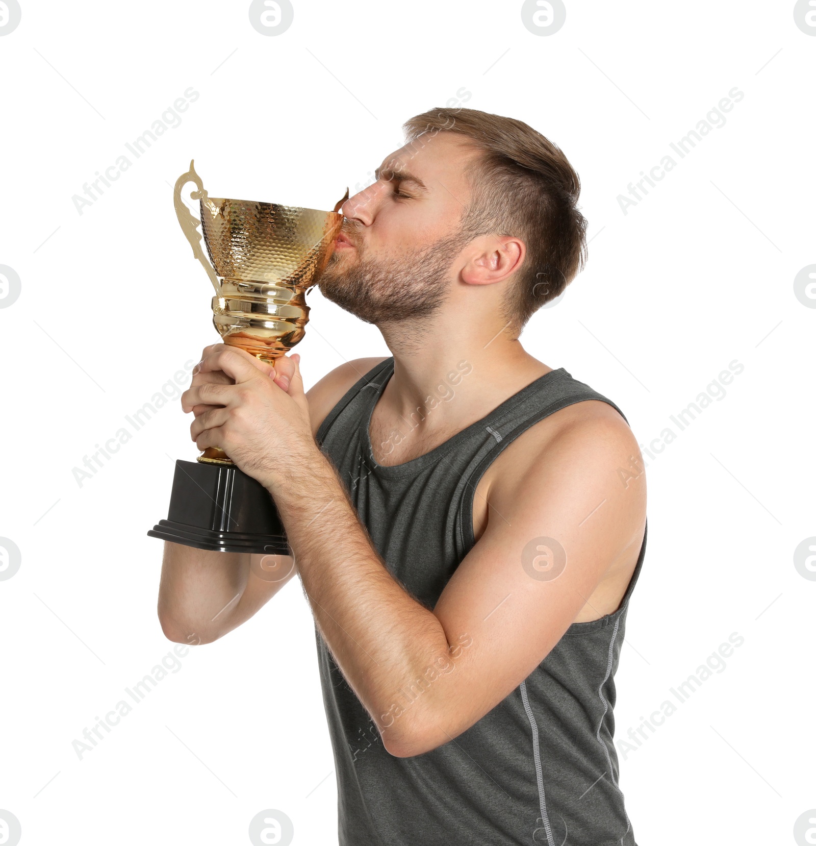 Photo of Portrait of young sportsman kissing gold trophy cup on white background