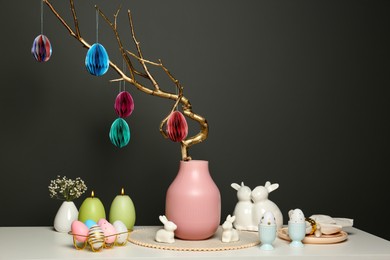 Photo of Beautiful festive composition with Easter decor on white table against dark background