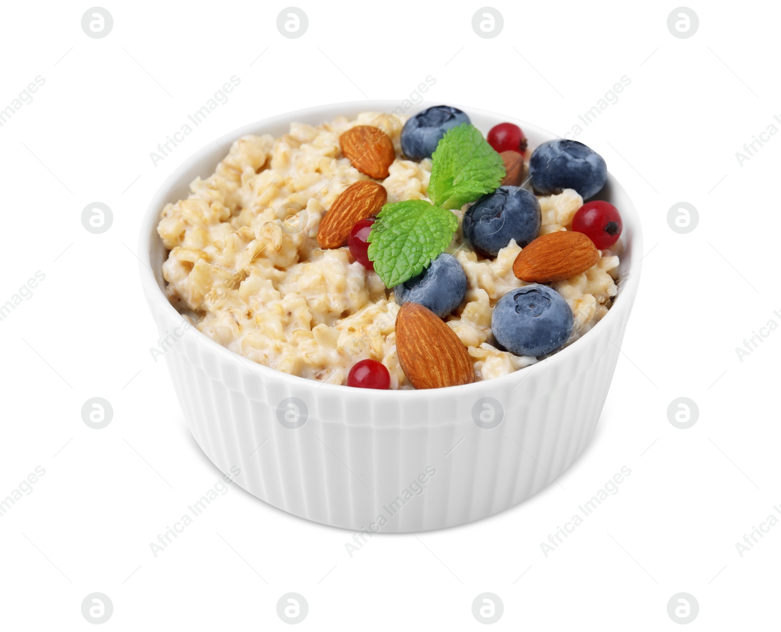 Photo of Ceramic bowl with oatmeal, berries. almonds and mint isolated on white