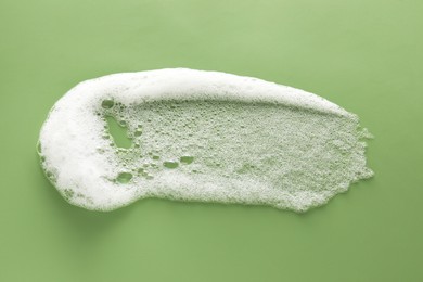 Smudge of white washing foam on olive background, top view