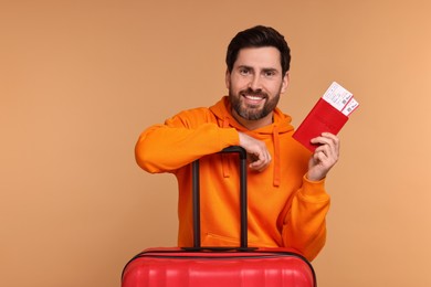 Photo of Smiling man with passport, suitcase and tickets on beige background. Space for text