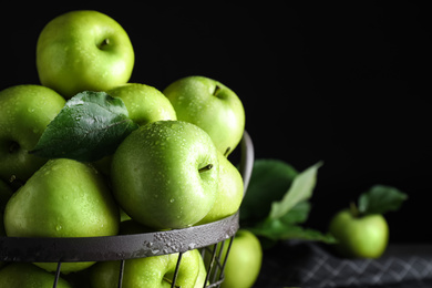 Photo of Juicy green apples in metal basket on black background, closeup