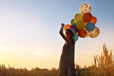 Photo of Young woman with colorful balloons outdoors in evening