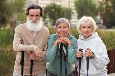 Photo of Group of senior people with Nordic walking poles outdoors