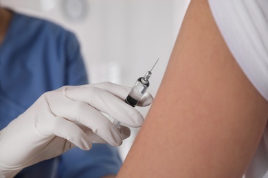 Doctor vaccinating woman against Covid-19 in clinic, closeup