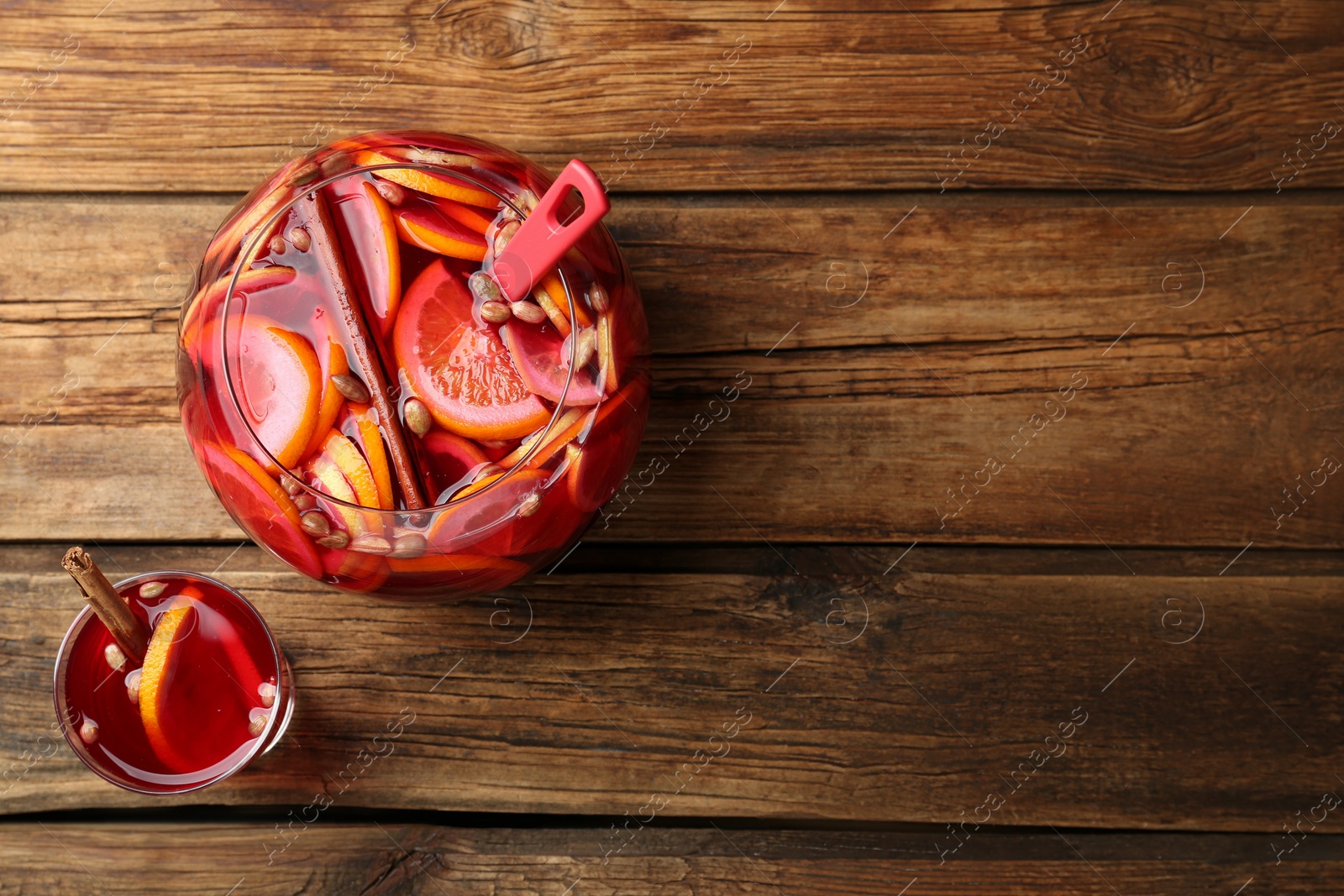 Photo of Glass and bowl with aromatic punch drink on wooden table, flat lay. Space for text