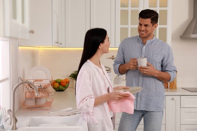 Happy couple with clean dishes in kitchen