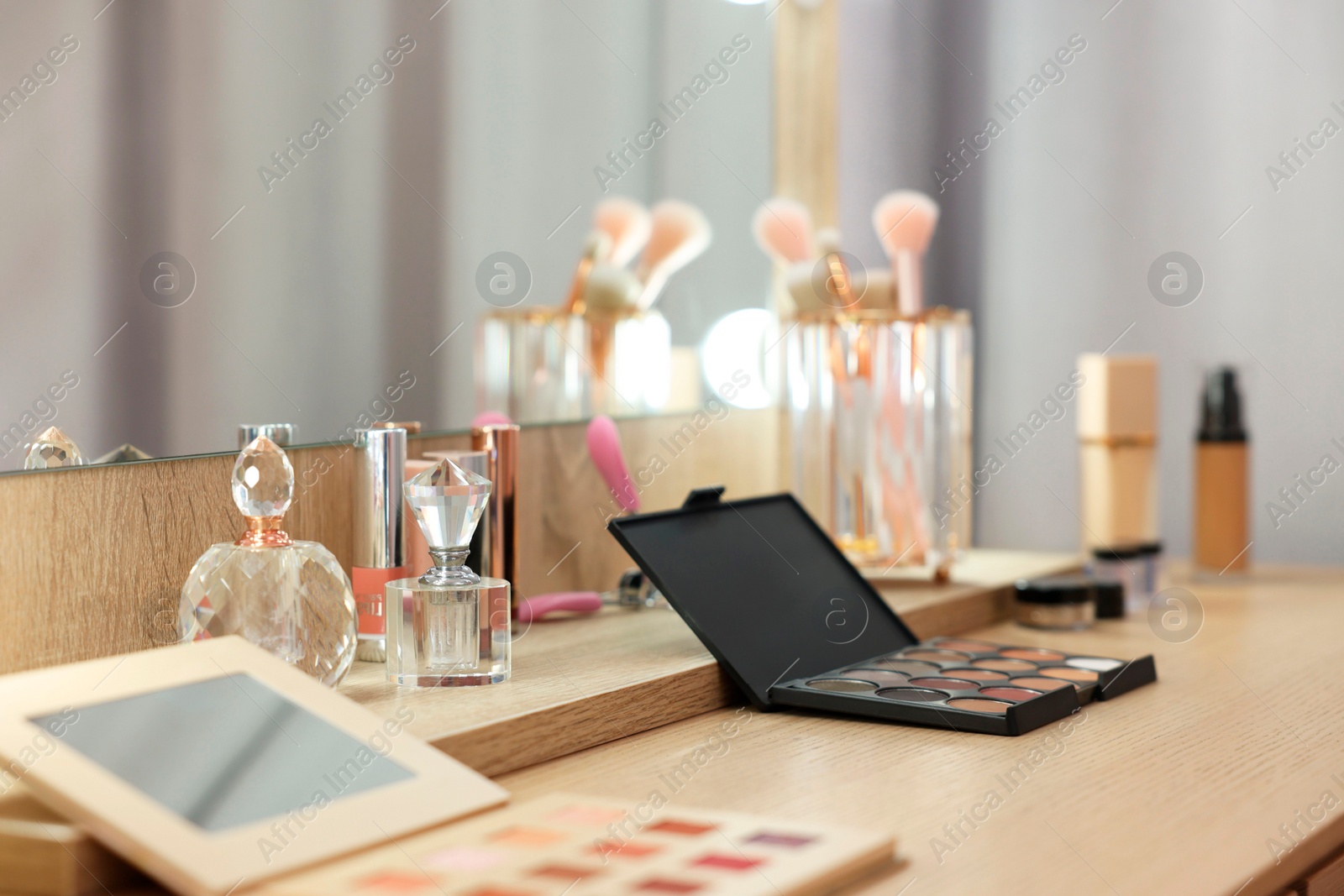 Photo of Cosmetic products and perfumes on wooden dressing table in makeup room