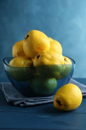 Photo of Tasty ripe quinces in bowl on blue wooden table