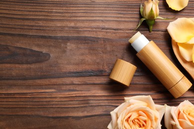 Photo of Lip balm and roses on wooden background, flat lay. Space for text