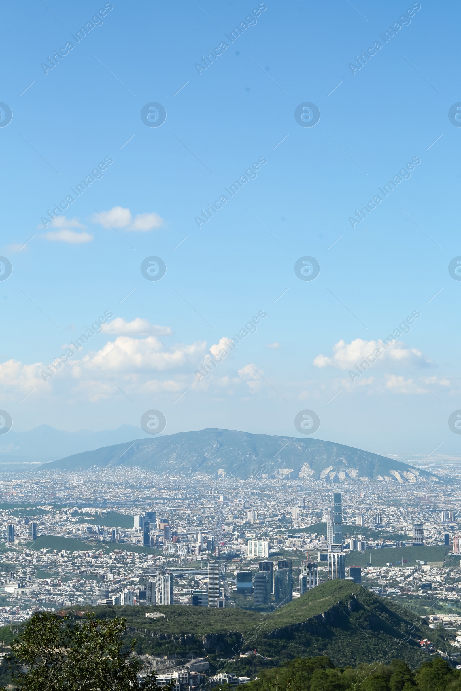 Photo of Picturesque view of city with trees, mountains and buildings under beautiful sky