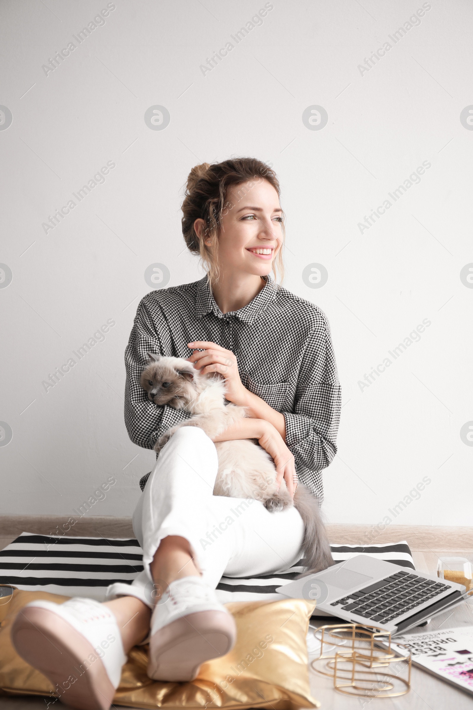 Photo of Young female blogger with laptop and cat indoors