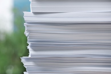 Photo of Stack of paper sheets against blurred background, closeup
