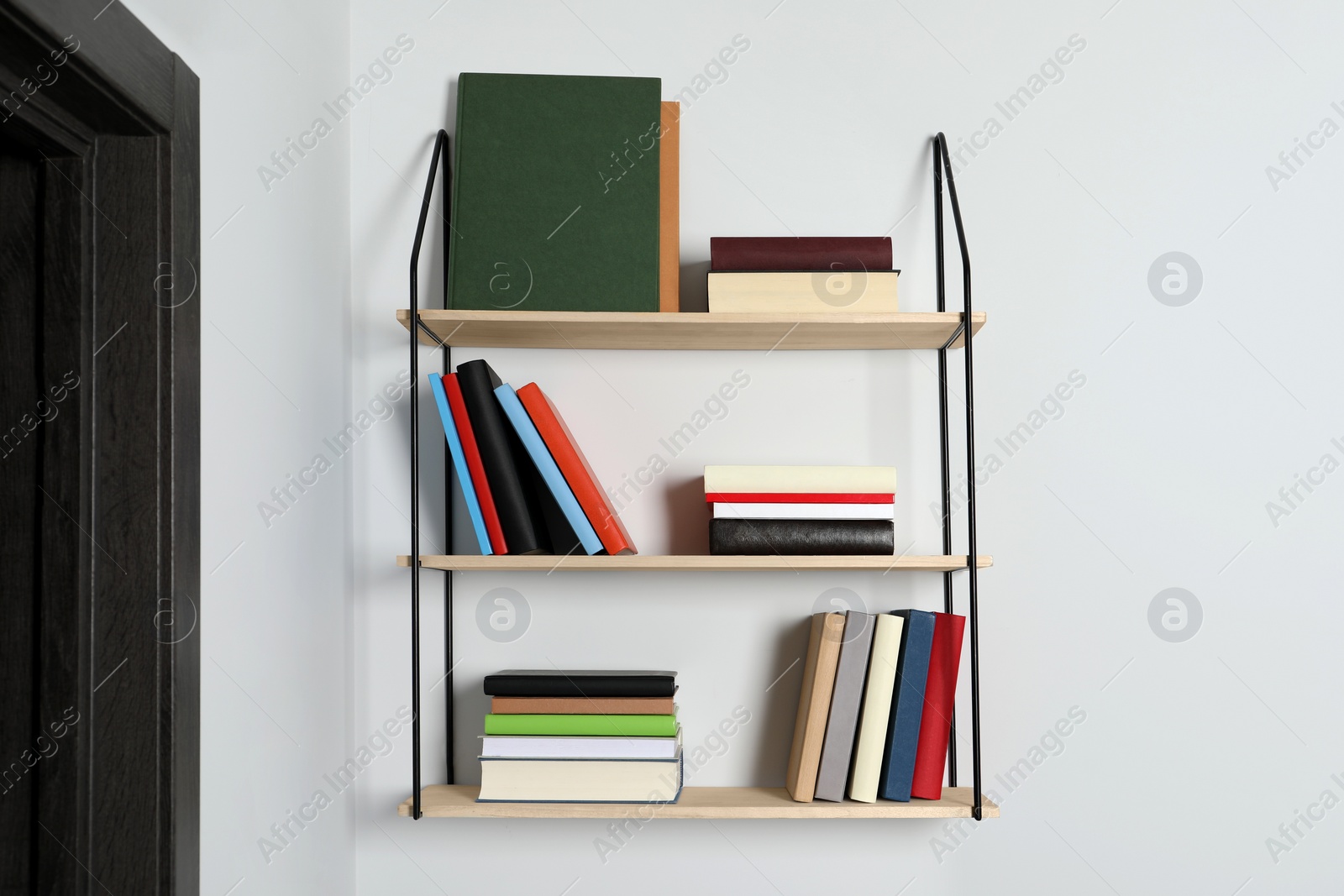 Photo of Shelves with many hardcover books on white wall