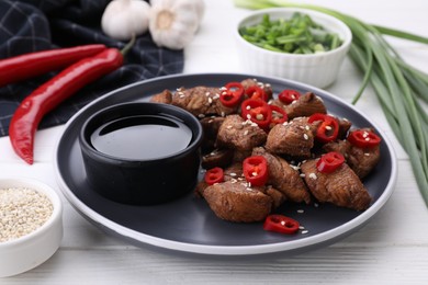 Photo of Plate with tasty soy sauce and roasted meat on white wooden table, closeup