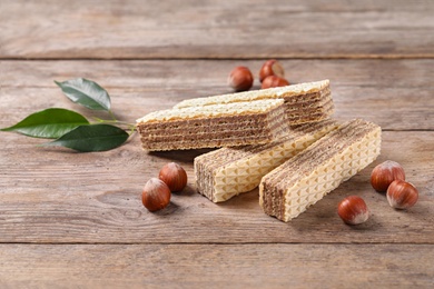 Photo of Delicious wafers with hazelnuts on brown wooden background