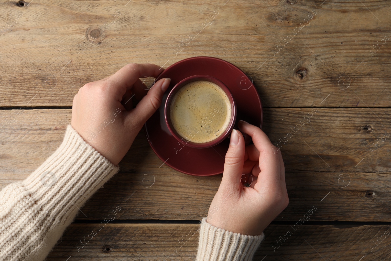 Photo of Woman with cup of hot aromatic coffee at wooden table, top view