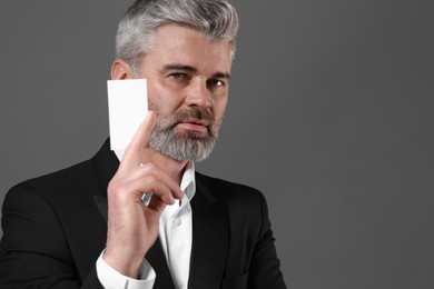 Photo of Handsome businessman holding blank business card on grey background. Space for text