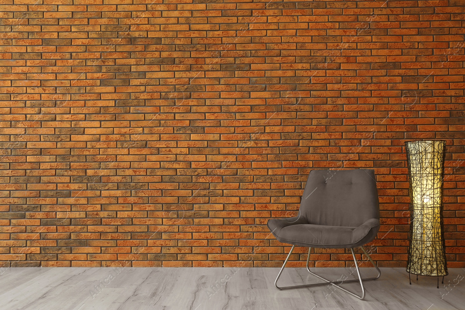 Photo of Grey modern chair and lamp near brick wall. Modern room interior