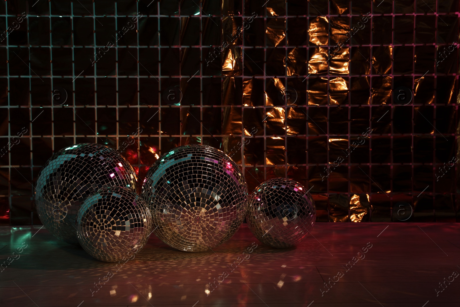 Photo of Many shiny disco balls on floor near foil party curtain. Space for text