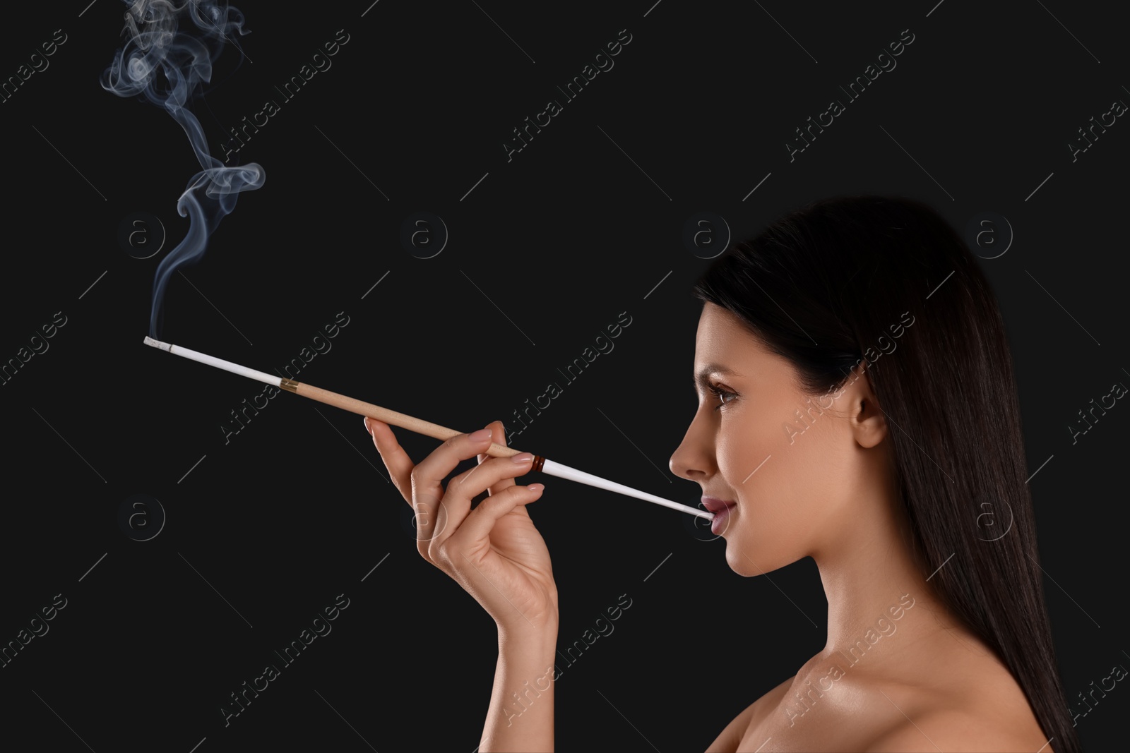 Photo of Woman using long cigarette holder for smoking on black background