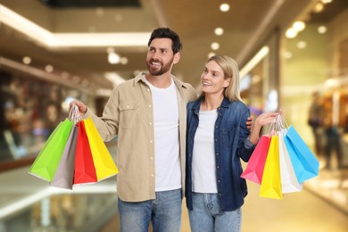 Image of Happy couple with shopping bags walking in mall