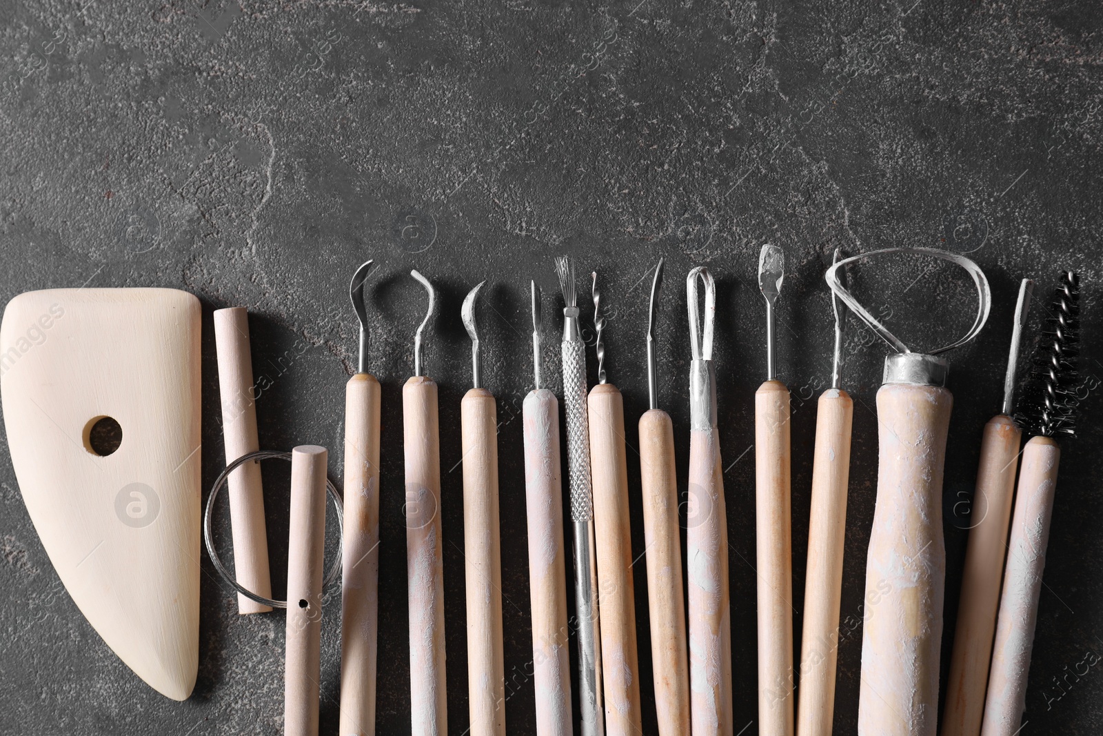 Photo of Set of different clay crafting tools on grey table, top view