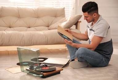 Man with vinyl record near turntable in living room