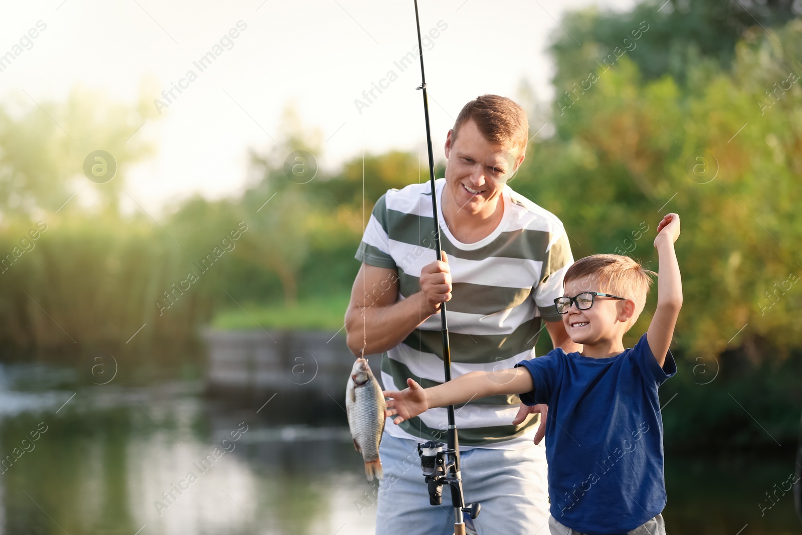 Photo of Dad and son fishing together on sunny day