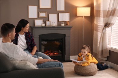 Photo of Happy family reading book together near fireplace at home