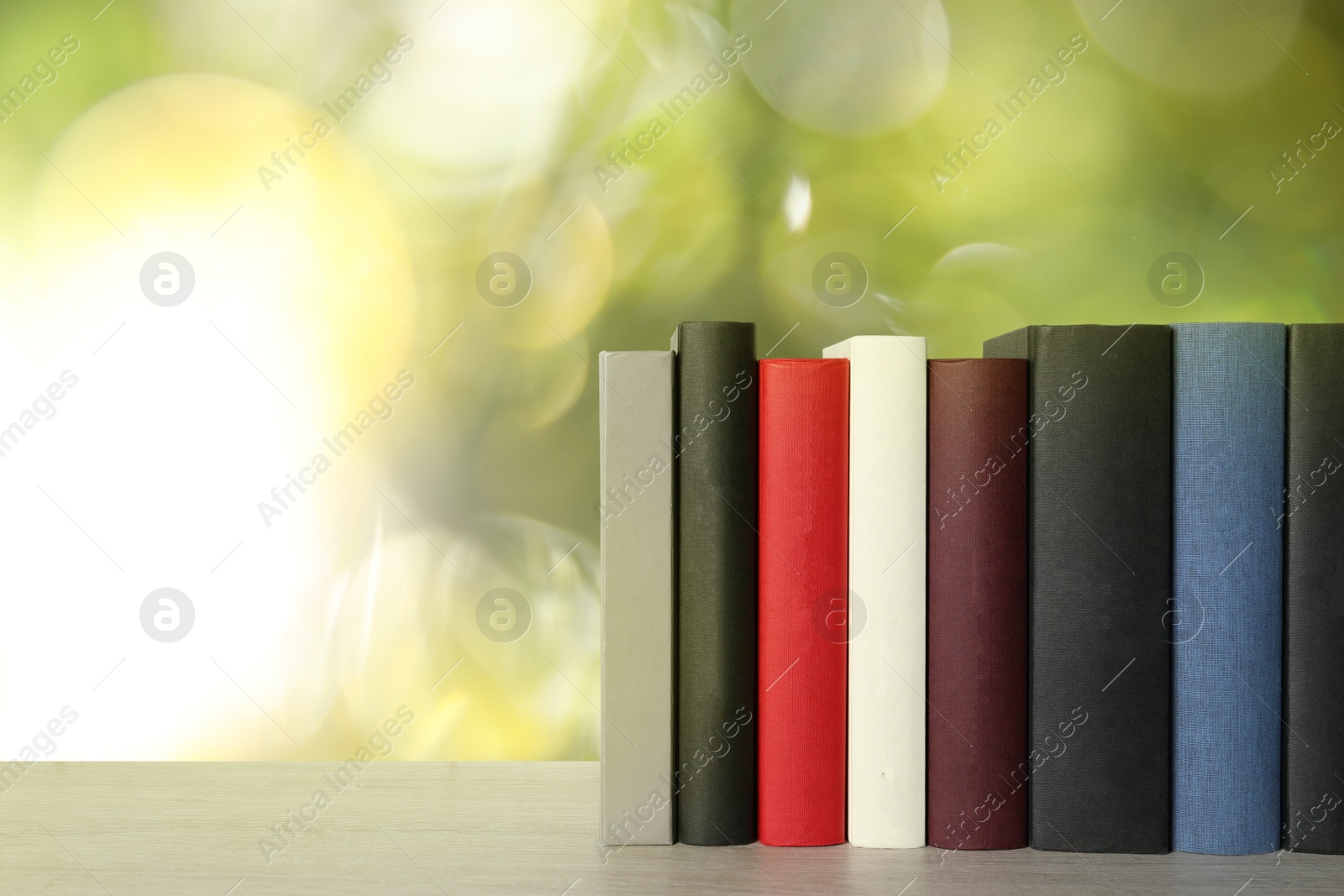 Image of Many hardcover books on table against blurred background, space for text