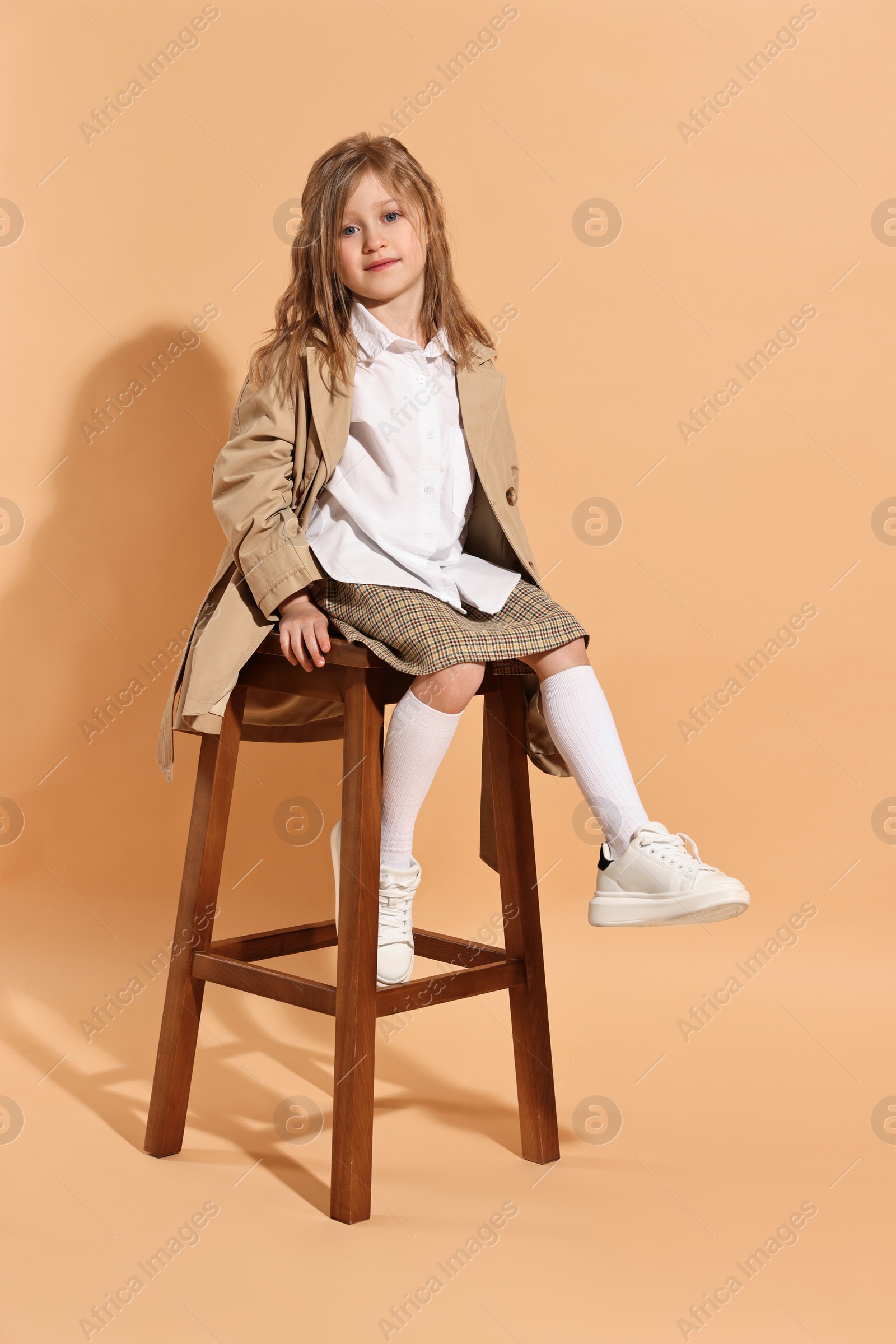 Photo of Fashion concept. Stylish girl posing on pale orange background