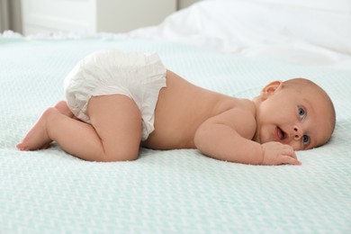 Photo of Cute little baby in diaper on bed at home