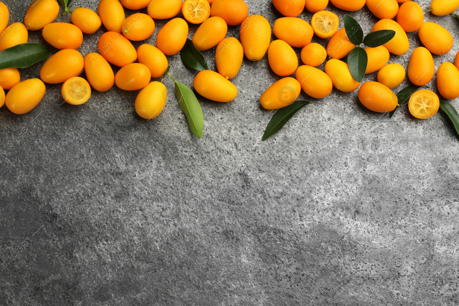 Photo of Fresh ripe kumquats on grey table, flat lay. Space for text