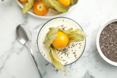 Photo of Delicious dessert decorated with physalis fruit on white marble table, flat lay