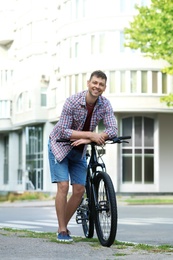 Photo of Handsome man with modern bicycle on city street