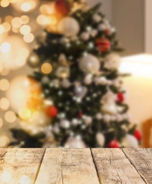 Empty wooden surface and blurred view of Christmas tree in room, space for text. Interior design