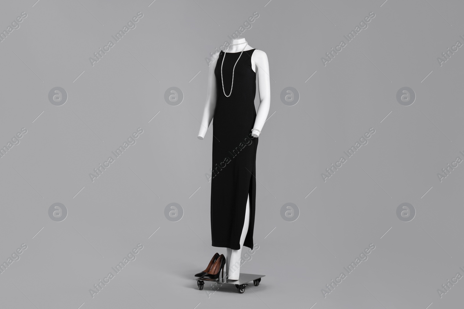 Photo of Female mannequin with necklace dressed in elegant black dress on grey background