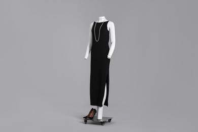 Photo of Female mannequin with necklace dressed in elegant black dress on grey background