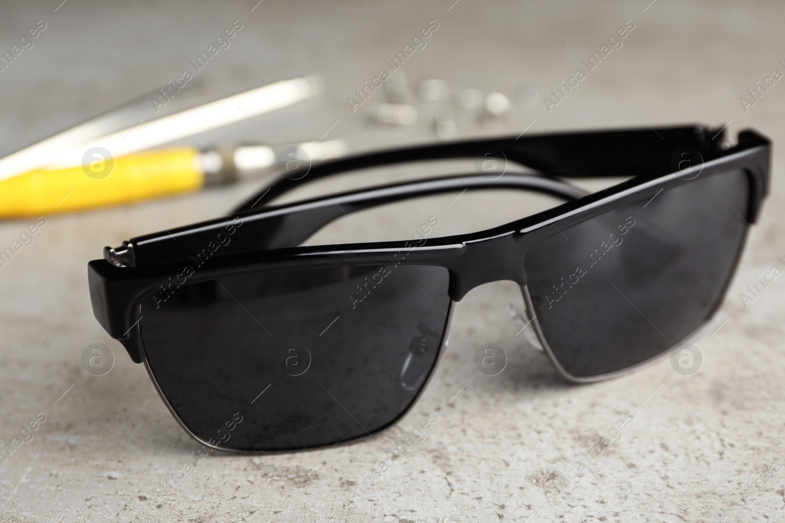 Photo of Stylish sunglasses and fixing tools on grey table