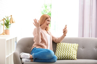 Photo of Woman using mobile phone for video chat in living room